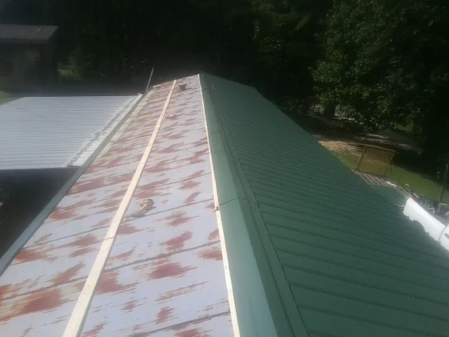 Old rusted panels beside newly installed green metal roofing — Wind Damage Roof Repair by Roofing Brothers in Rickman