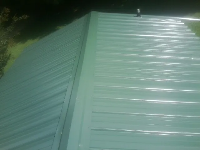 New green metal panels meeting at the ridge of a roof — Flat Roof Repair work by our crew in Rickman