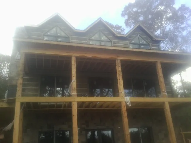 Dormers and porch framing on a large log home under construction — Roof Coating work by our crew in Rickman