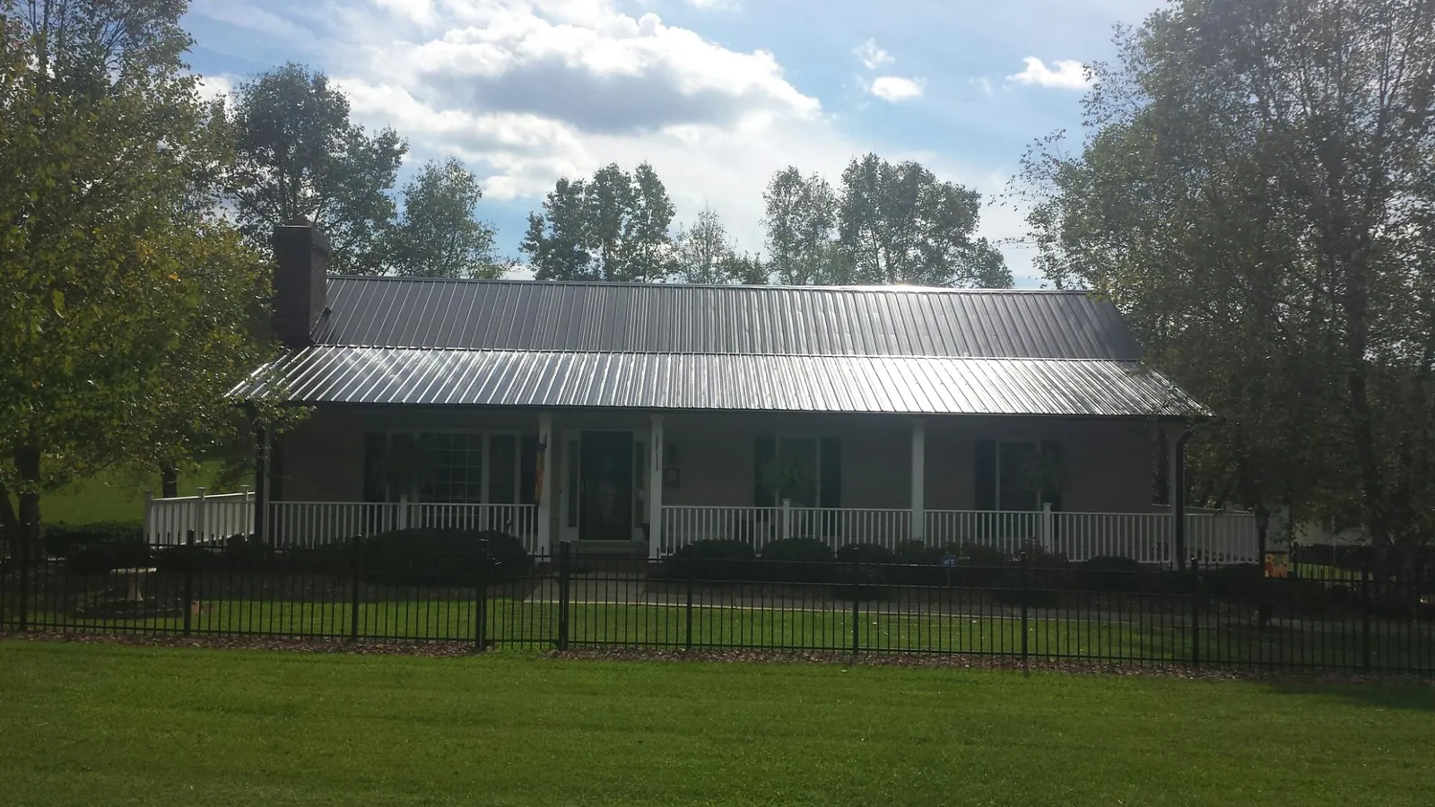 Gray metal roof on a brick ranch with a full width front porch — Gutter Guard Installation work by our crew in Rickman