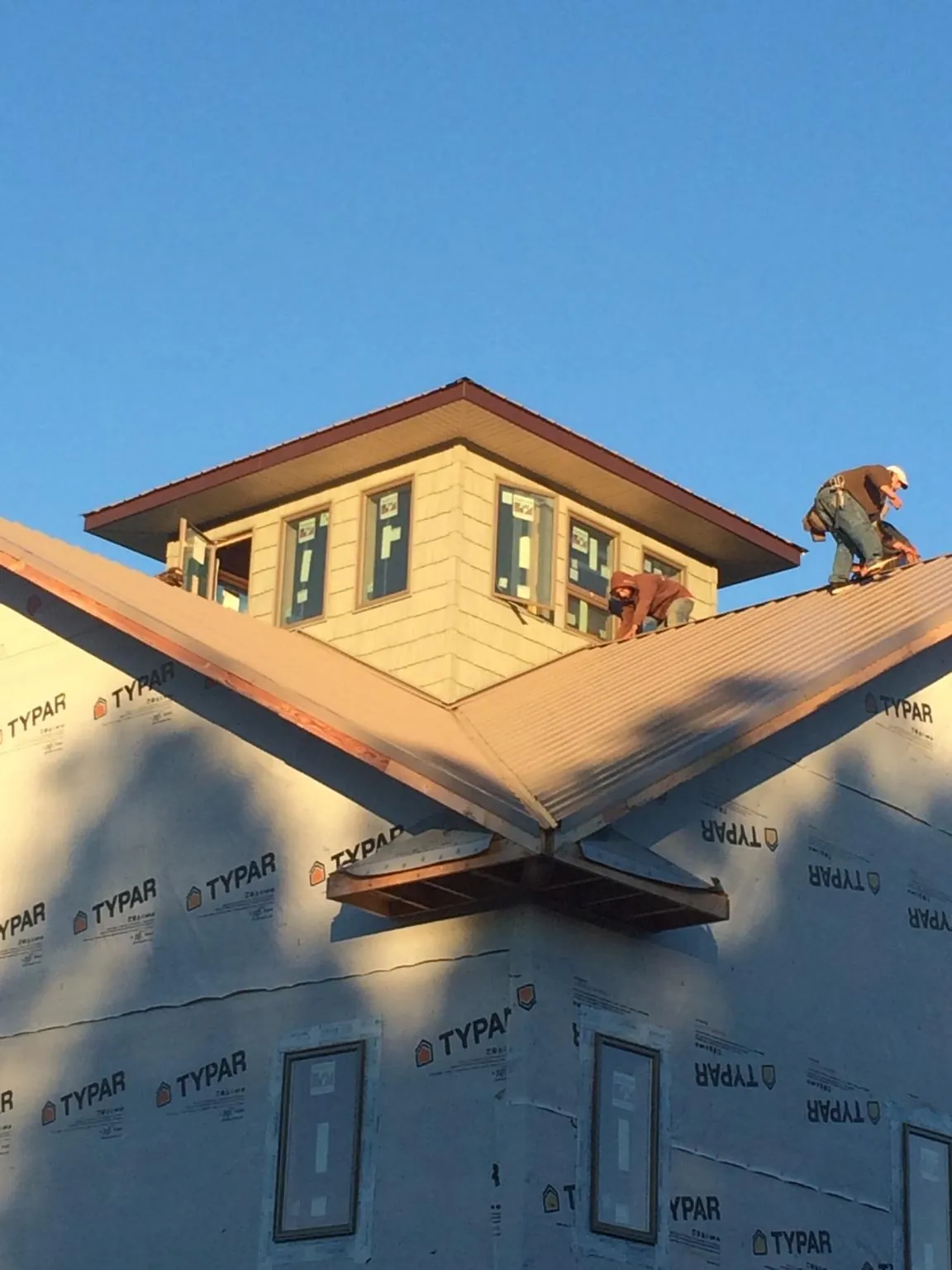 Roofers working around a rooftop cupola on a new metal roof at sunset — Roof Waterproofing in Rickman by Roofing Brothers